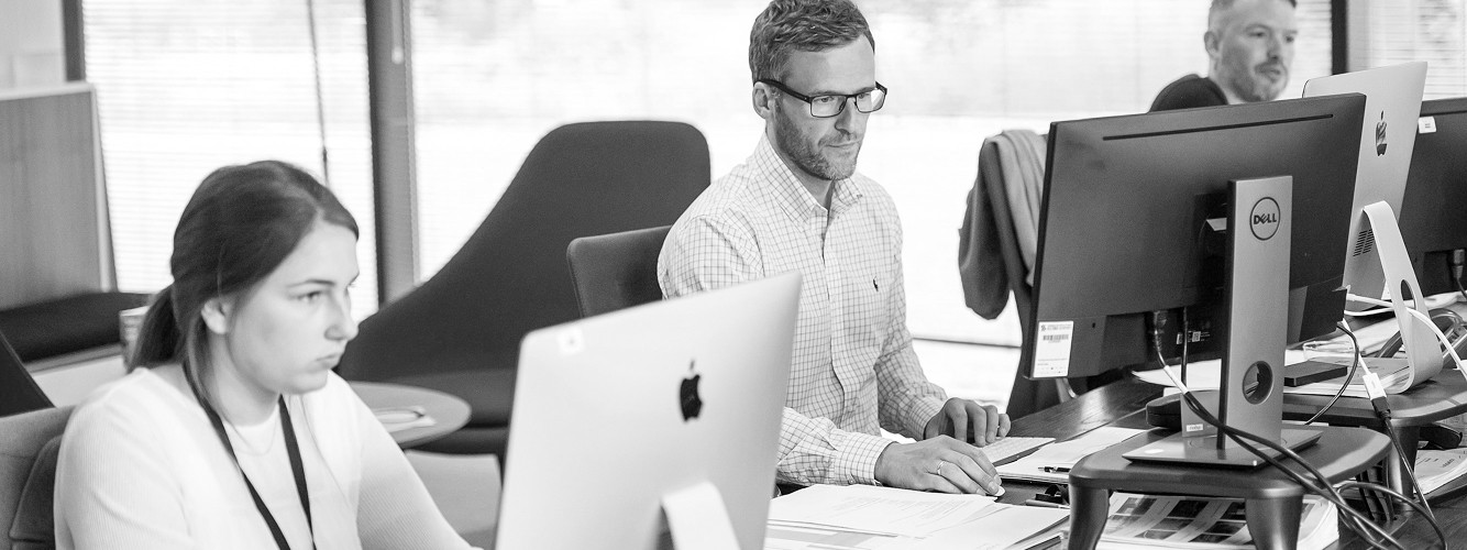 Team of three employees having a meeting at a table in a bright modern office.